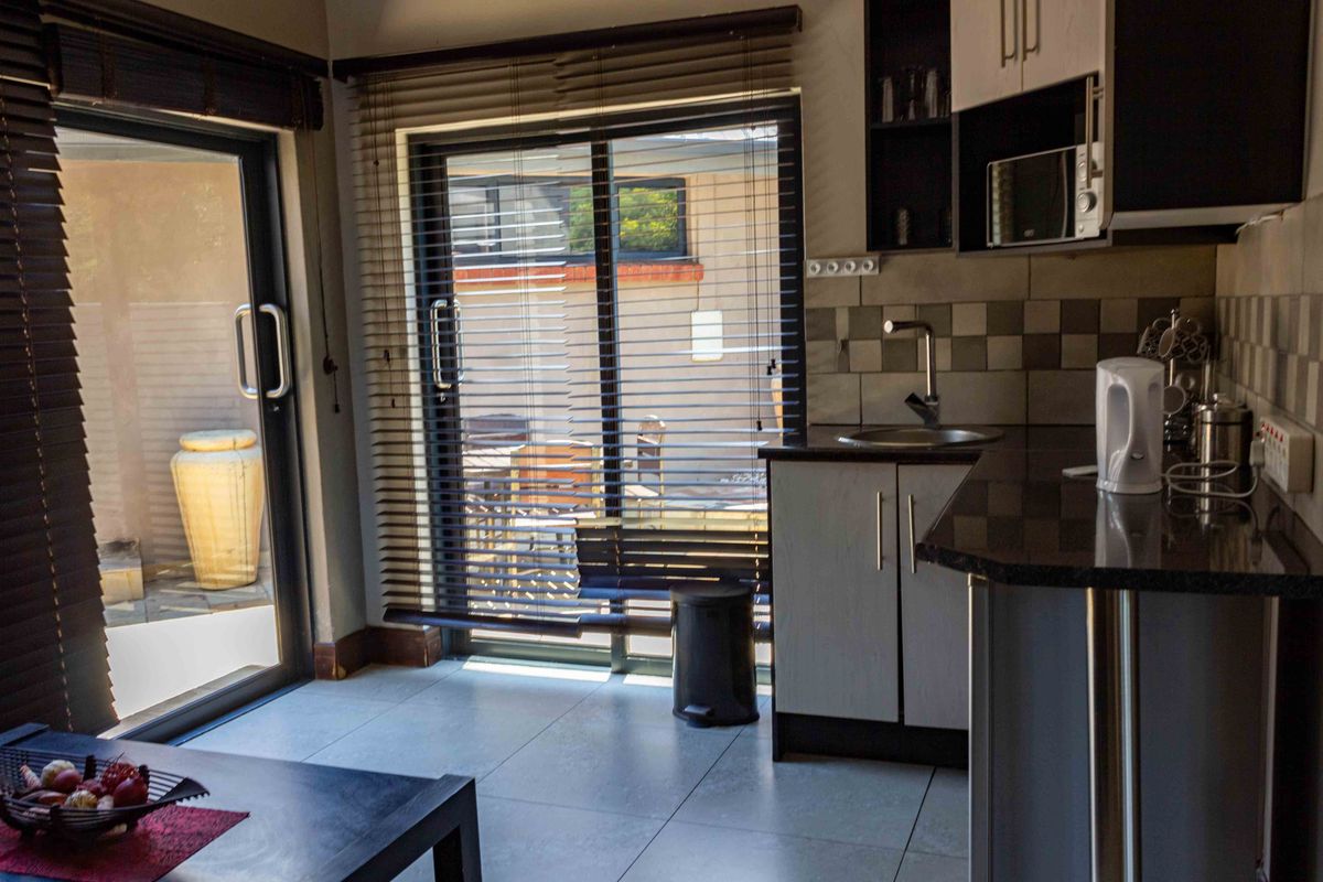 Compact kitchen area featuring built-in cabinetry, granite countertops, and direct access to an outdoor patio through sliding glass doors.