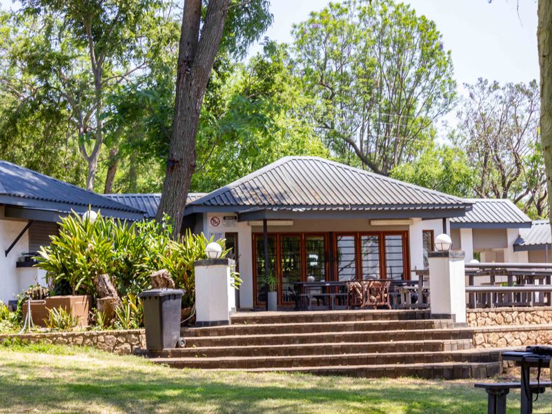 Rear view of the farm property featuring a covered patio area with timber-framed glass doors, stone retaining walls, and brick stairs leading to the garden.