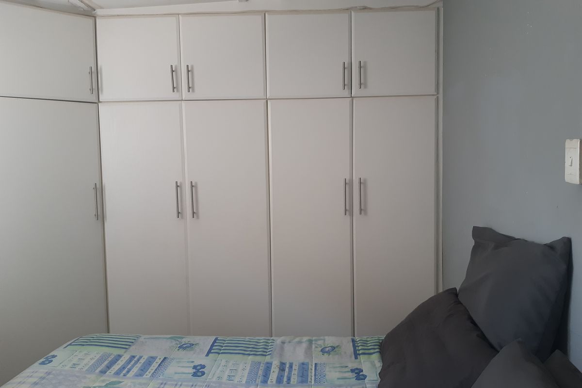 A bedroom featuring built-in white cabinetry with modern handles, providing ample storage space.