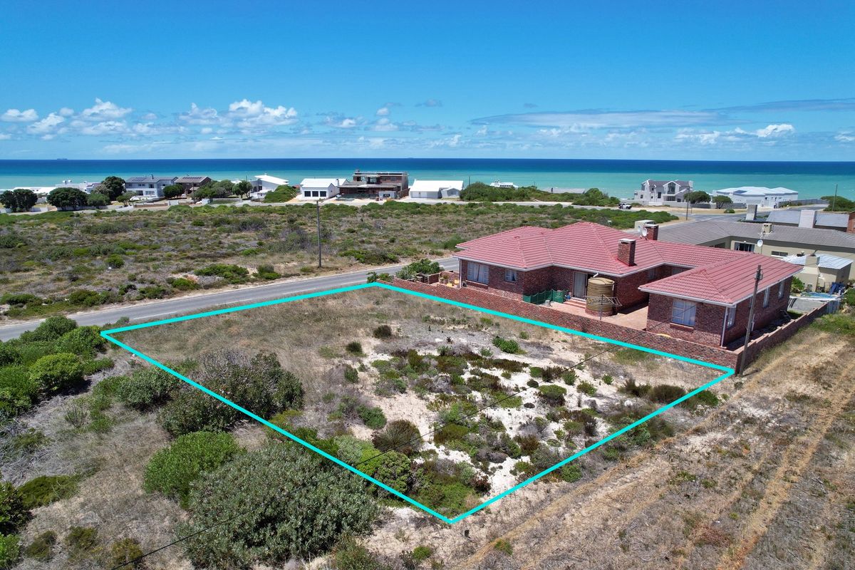 Aerial view of a vacant residential plot situated in a coastal neighborhood, featuring natural vegetation and clear boundary lines.