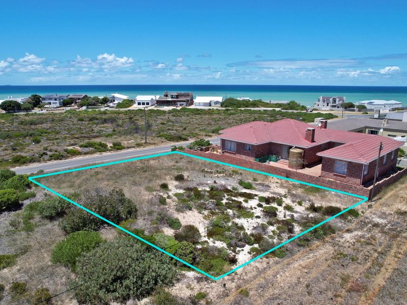 Aerial view of a vacant residential plot situated in a coastal neighborhood, featuring natural vegetation and clear boundary lines.