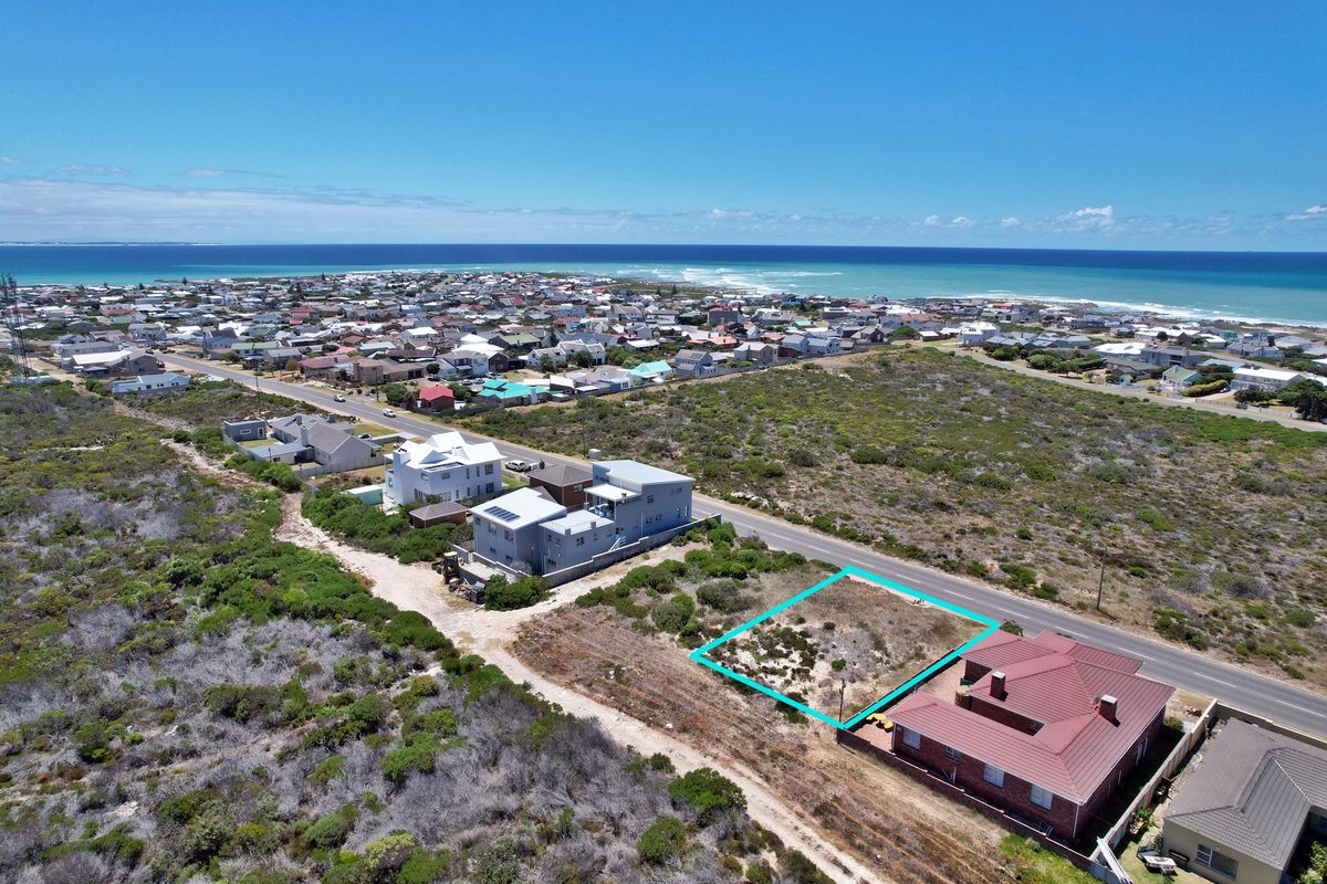 Aerial view of a vacant residential plot situated in a coastal neighborhood, highlighting its proximity to the ocean and surrounding residential development.