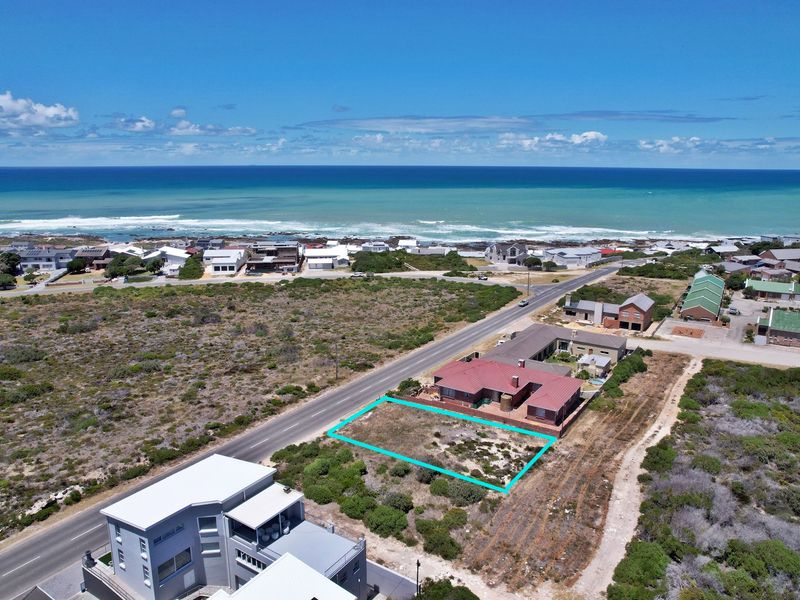 Aerial view of a vacant residential plot situated in a coastal neighborhood, highlighting the property boundaries and proximity to the ocean.