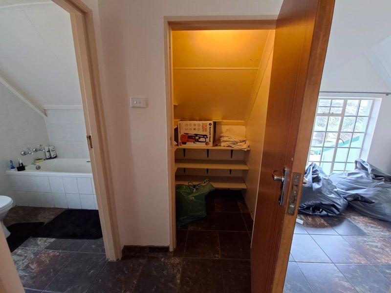 A hallway area featuring built-in storage shelving, tiled flooring, and access to an adjacent bathroom.
