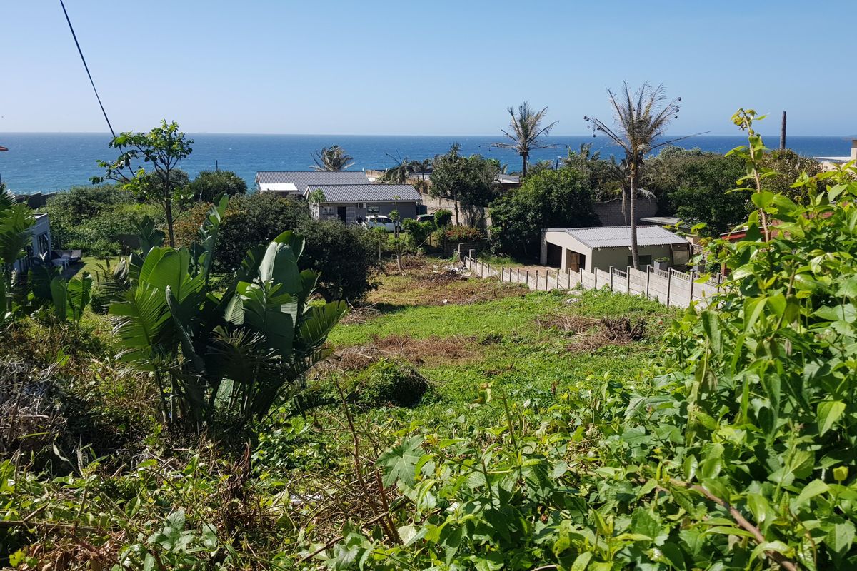 A sloped residential plot featuring coastal views, surrounded by established neighborhood homes and mature greenery, offering potential for development.