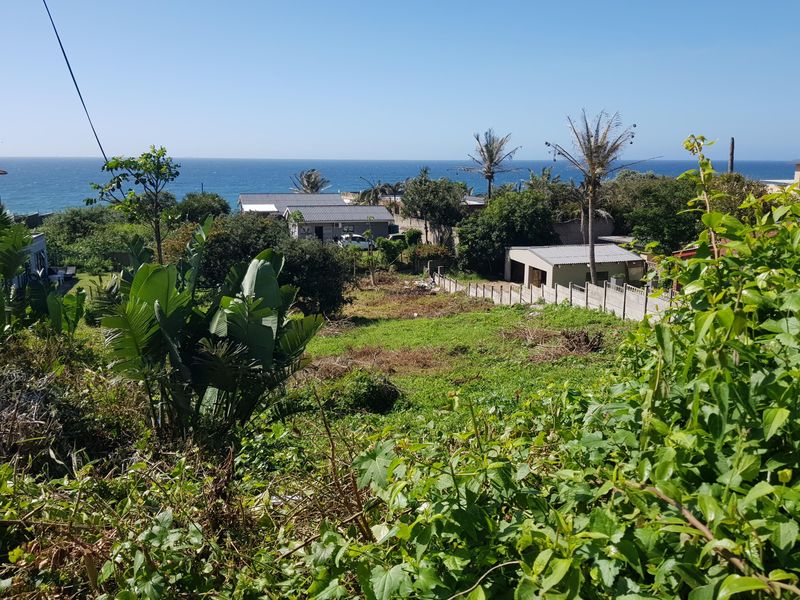 A sloped residential plot featuring coastal views, surrounded by established neighborhood homes and mature greenery, offering potential for development.