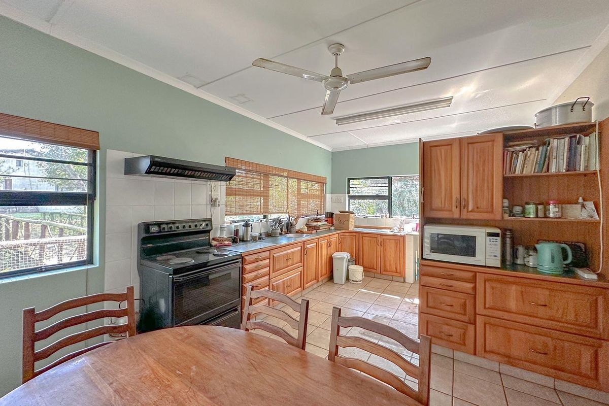 A functional kitchen featuring wooden cabinetry, tiled flooring, a built-in stove with extractor fan, and ample natural light from multiple windows.