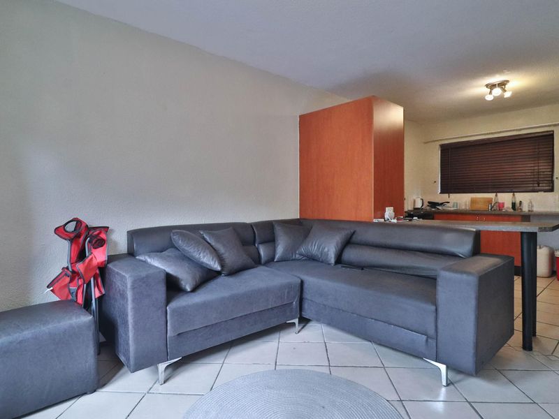 Open plan living area featuring tiled floors and a functional kitchen with built-in cabinetry and a breakfast bar.