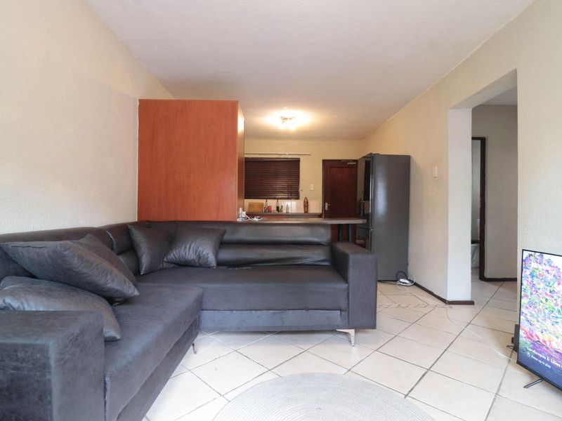 Open-plan living area featuring ceramic tiled flooring and a functional kitchen space with a breakfast counter.