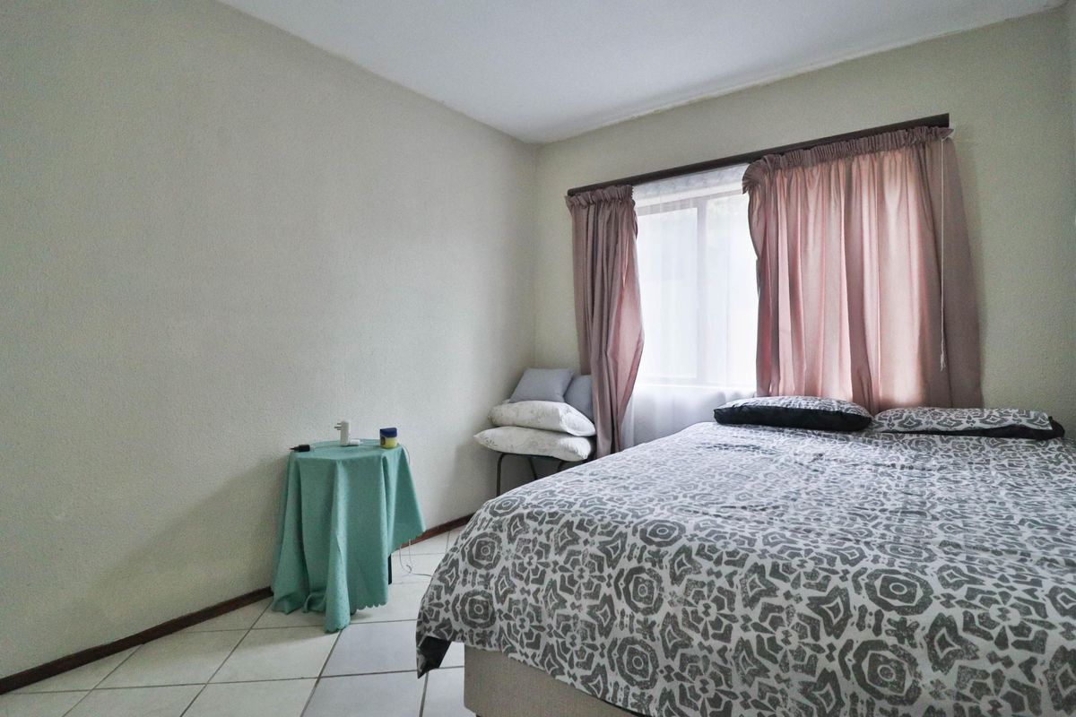 A functional bedroom featuring tiled flooring and a window with an installed curtain rod.