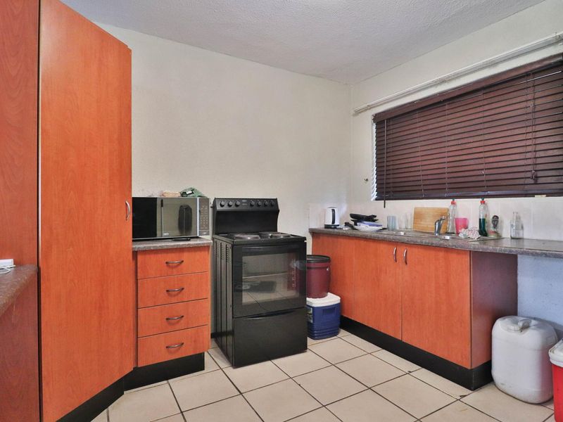 A functional kitchen featuring laminate cabinetry, a freestanding stove, and ceramic tile flooring, offering a dated aesthetic ready for modernization.