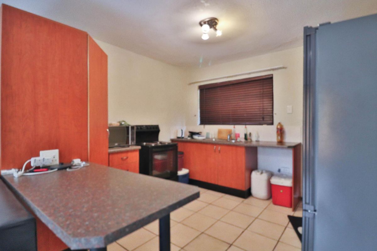 A functional kitchen featuring laminate cabinetry, a freestanding oven, stainless steel sink, and tiled flooring, offering a practical layout for daily meal preparation.