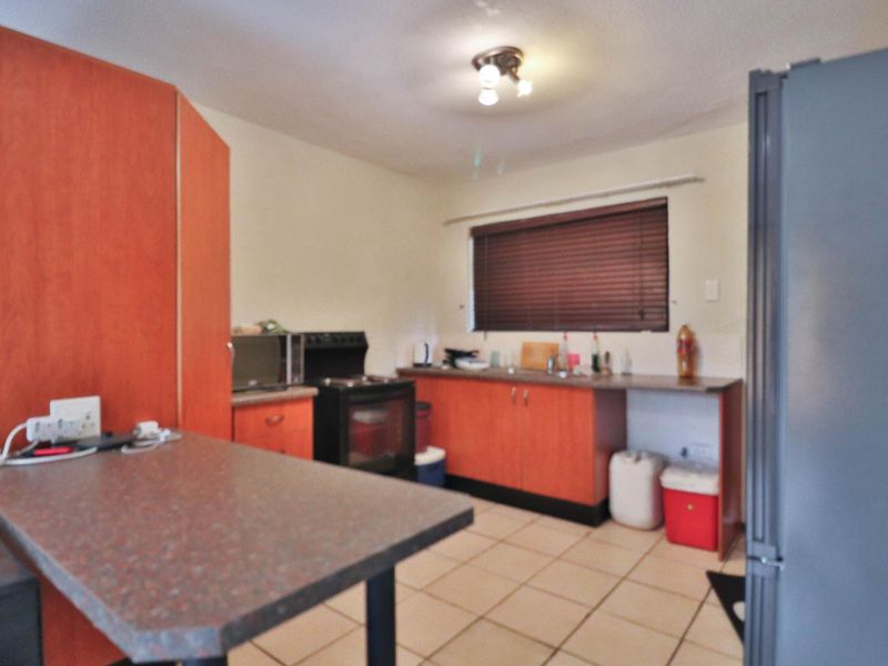 A functional kitchen featuring laminate cabinetry, a freestanding oven, stainless steel sink, and tiled flooring, offering a practical layout for daily meal preparation.