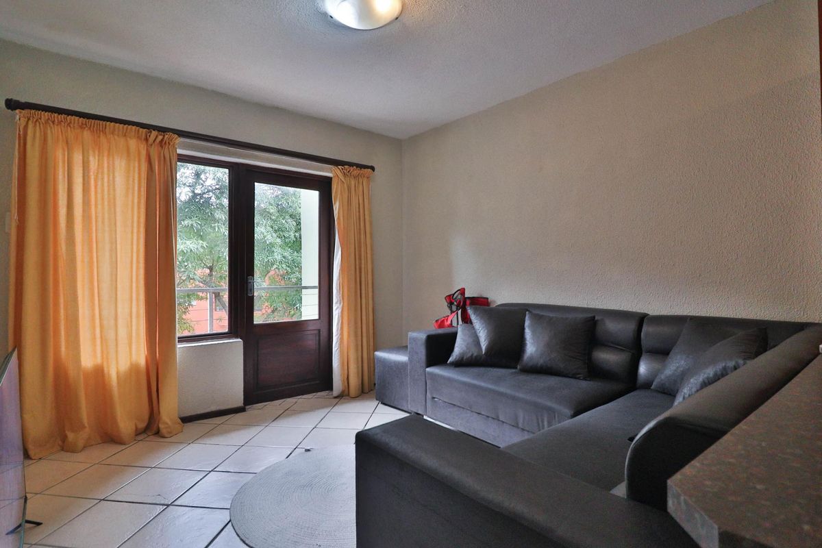A living room featuring tiled flooring and a glass panel door providing access to an outdoor area.
