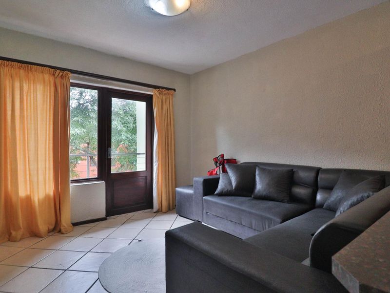 A living room featuring tiled flooring and a glass panel door providing access to an outdoor area.