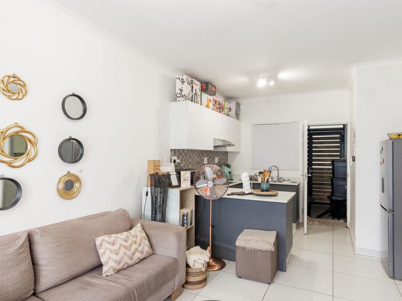Open-plan living area featuring a compact kitchen with modern cabinetry, tiled flooring, and a functional layout suitable for apartment living.