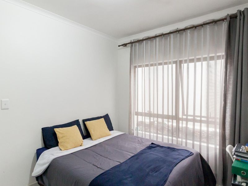 A well-lit bedroom featuring neutral walls, coving, and a large window with installed curtain rod and window treatments.