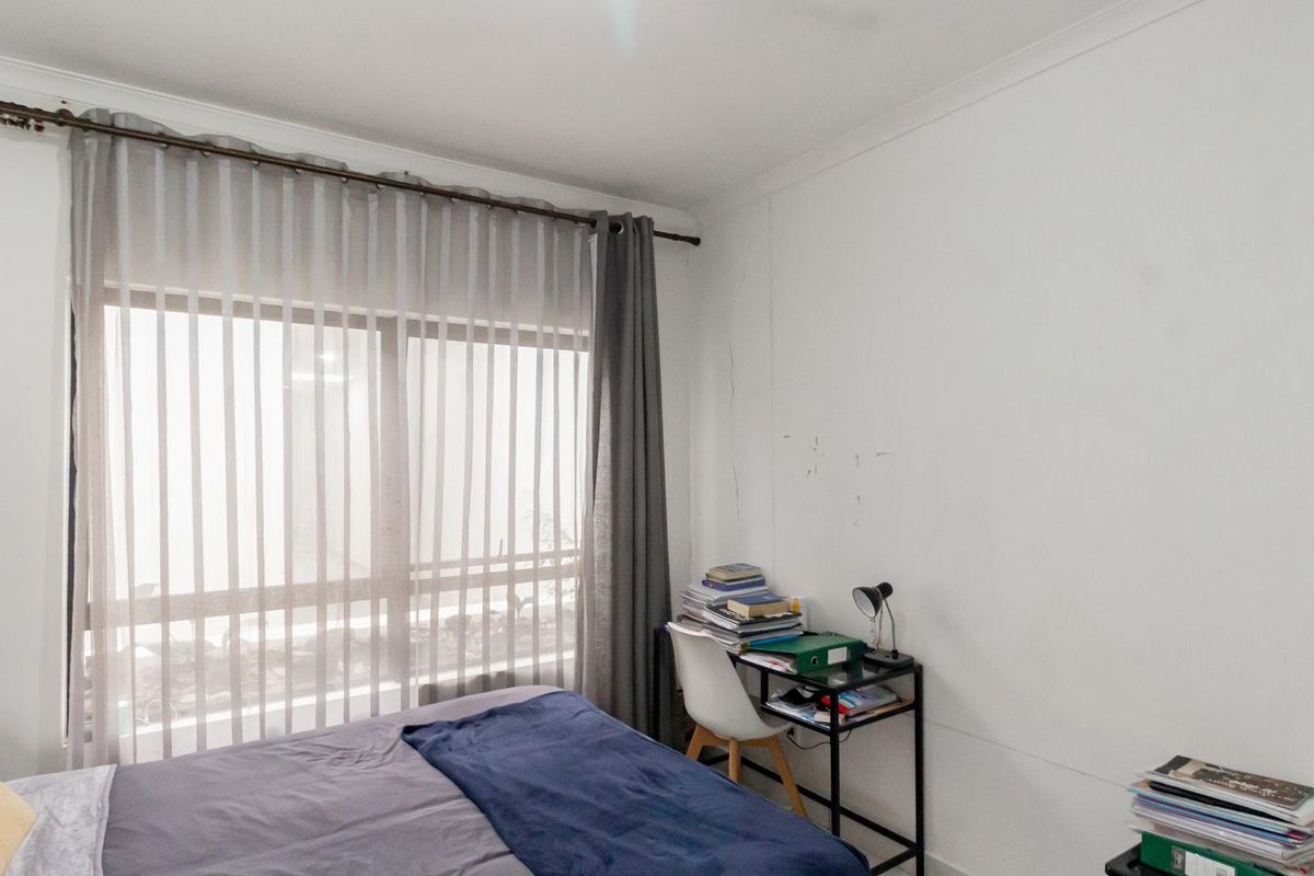 A bedroom featuring a large window with curtain rod and coving, showing visible signs of wear on the wall surfaces.
