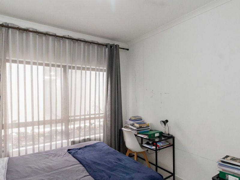 A bedroom featuring a large window with curtain rod and coving, showing visible signs of wear on the wall surfaces.