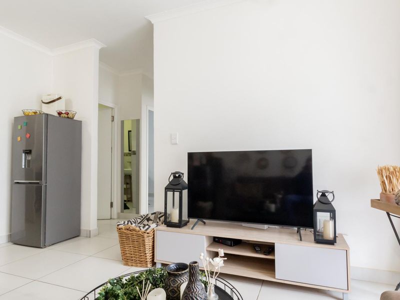 A bright living area featuring neutral tiled flooring and clean white walls, providing a versatile space for relaxation.