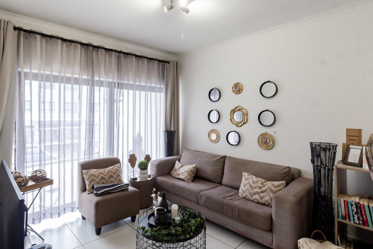 A bright living room featuring tiled flooring and a large sliding glass door with curtain tracks, providing ample natural light.