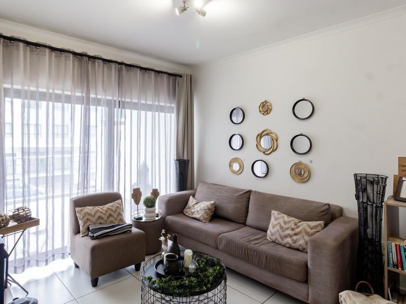 A bright living room featuring tiled flooring and a large sliding glass door with curtain tracks, providing ample natural light.