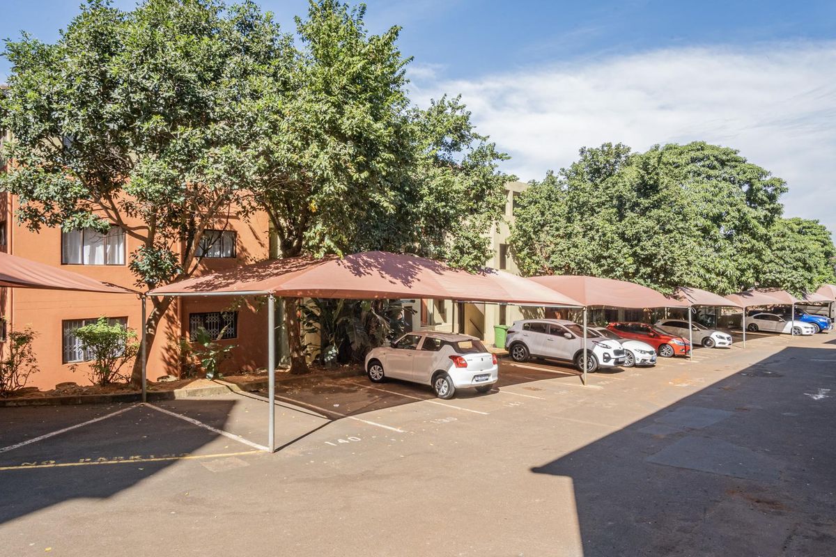 Exterior view of the apartment complex showing the designated parking area with installed shade cloth carports.