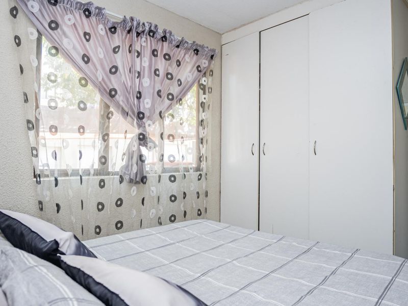 A bedroom featuring built-in cupboards and a window, providing functional storage and natural light.