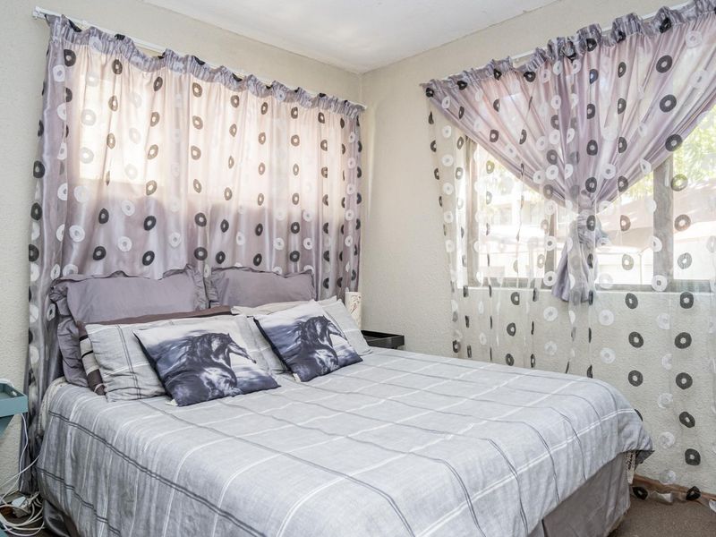 A functional bedroom featuring dual windows with installed curtain rails, providing natural light and a neutral backdrop for personalization.