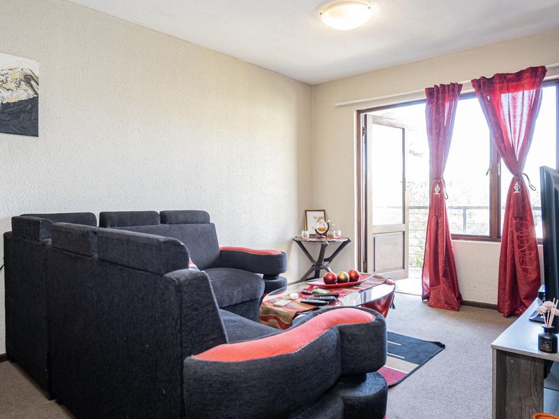 A living room featuring carpet flooring and a sliding glass door providing access to an outdoor area.