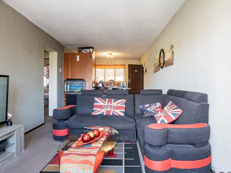 Open plan living area featuring textured walls and carpeted flooring, providing a functional space that could benefit from modern updates and refreshed finishes.