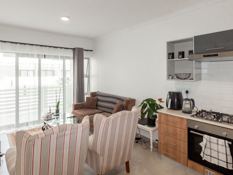 Open-plan living area featuring a modern kitchen with built-in appliances, subway tile backsplash, and sliding doors leading to a balcony.