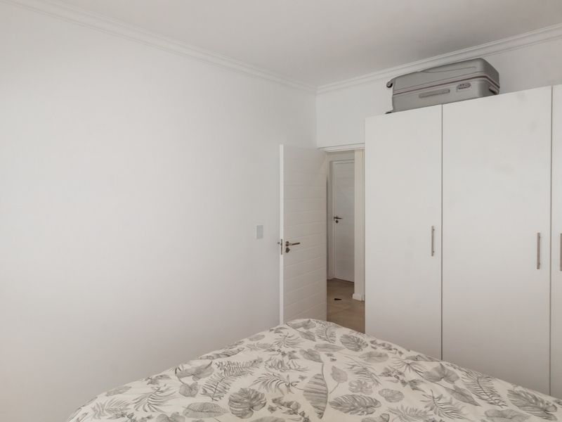 A clean bedroom featuring a white built-in wardrobe and neutral finishes, providing a bright and functional living space.