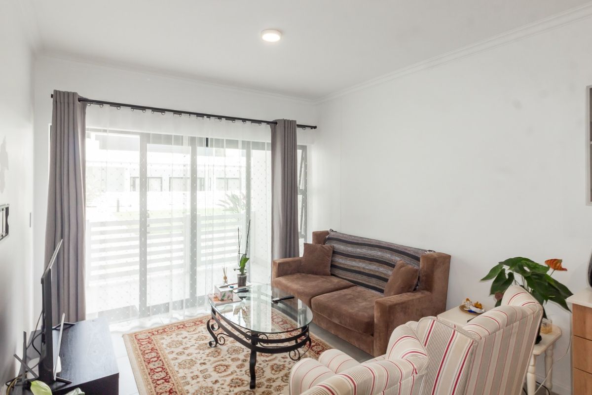 A bright living room featuring a large sliding glass door, built-in shelving, and neutral finishes, offering a comfortable space with direct access to the outdoors.
