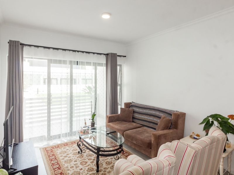A bright living room featuring a large sliding glass door, built-in shelving, and neutral finishes, offering a comfortable space with direct access to the outdoors.