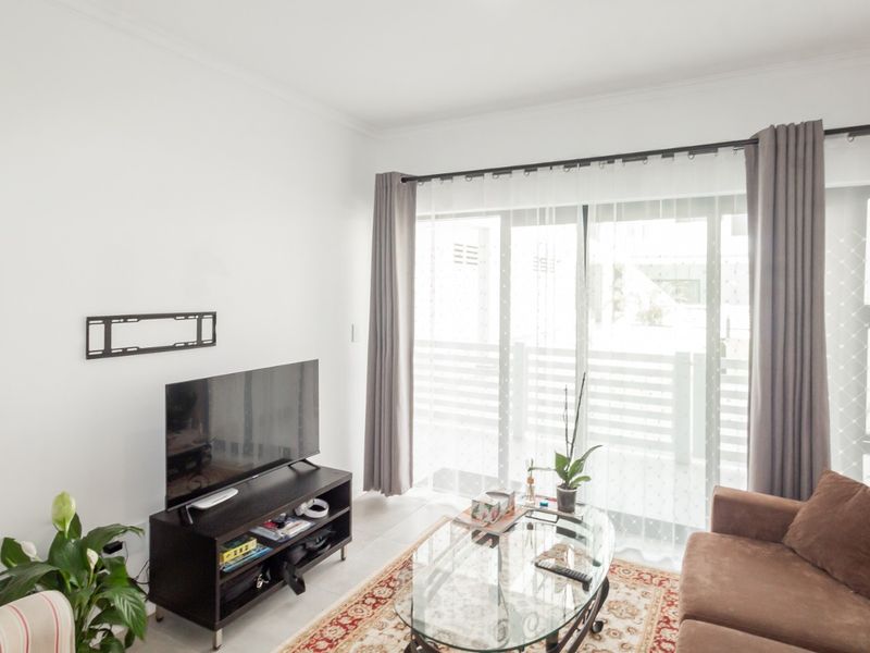 A bright living room featuring tiled flooring and large sliding glass doors that provide access to an outdoor balcony area.