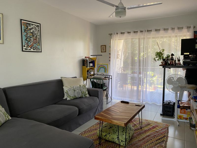 A living room featuring tiled flooring, a ceiling fan, and a large sliding glass door providing access to an outdoor patio area.