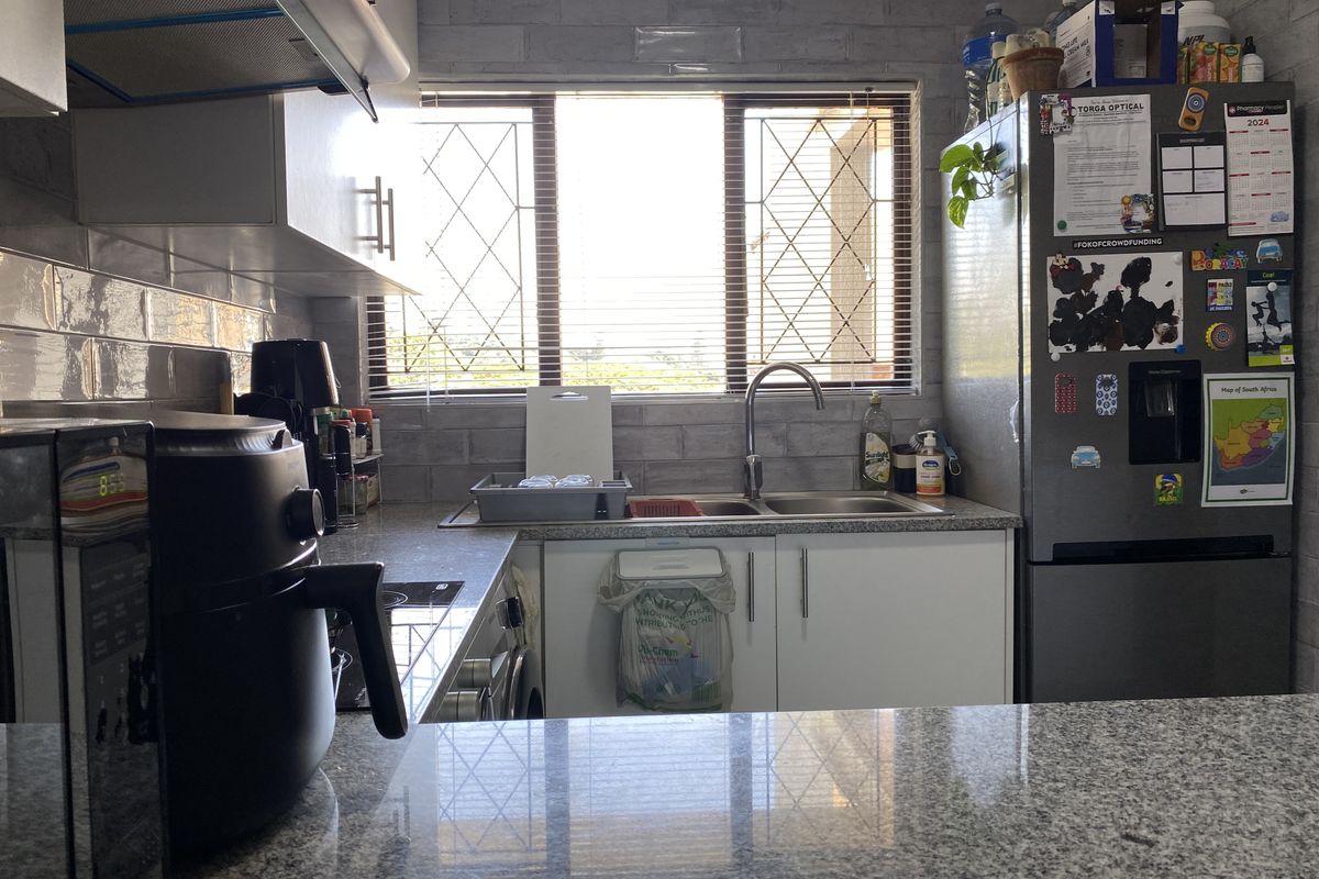 A functional kitchen featuring granite countertops, subway tile backsplash, stainless steel sink, and built-in cabinetry with an integrated extractor fan.