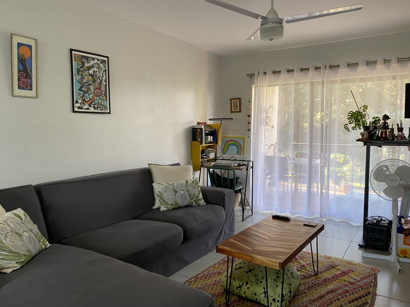 A comfortable living room featuring tiled flooring, a ceiling fan, and large sliding glass doors that provide access to an outdoor patio area.