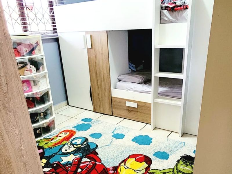A bedroom featuring tiled flooring and a window fitted with security bars and venetian blinds.