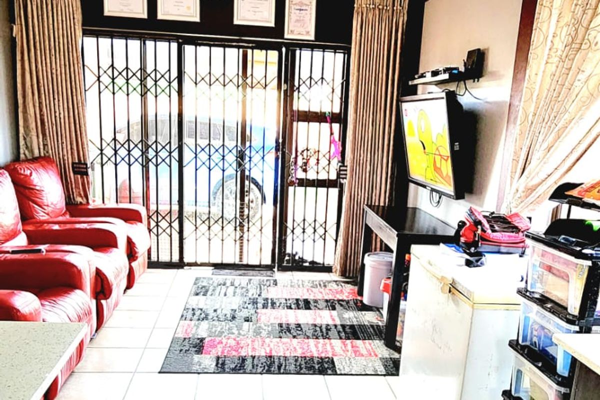 A living area featuring tiled flooring, a security gate, and an integrated air conditioning unit, providing a functional space with direct access to the exterior.