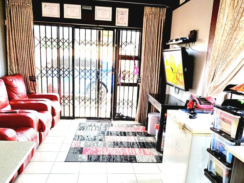 A living area featuring tiled flooring, a security gate, and an integrated air conditioning unit, providing a functional space with direct access to the exterior.