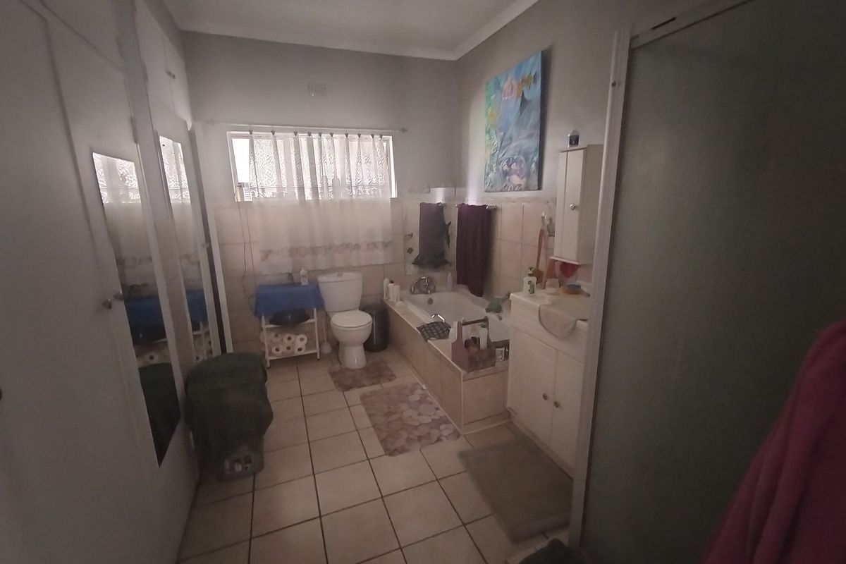 A functional bathroom featuring a bathtub, separate shower enclosure, vanity cabinet, and built-in storage cupboards with tiled flooring throughout.