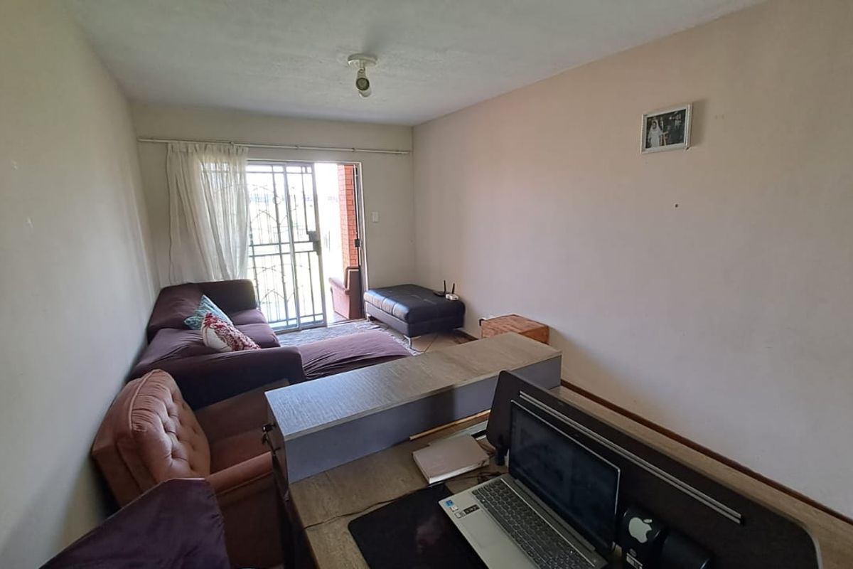 A living room area featuring a sliding glass door with a security gate, providing access to an outdoor space.