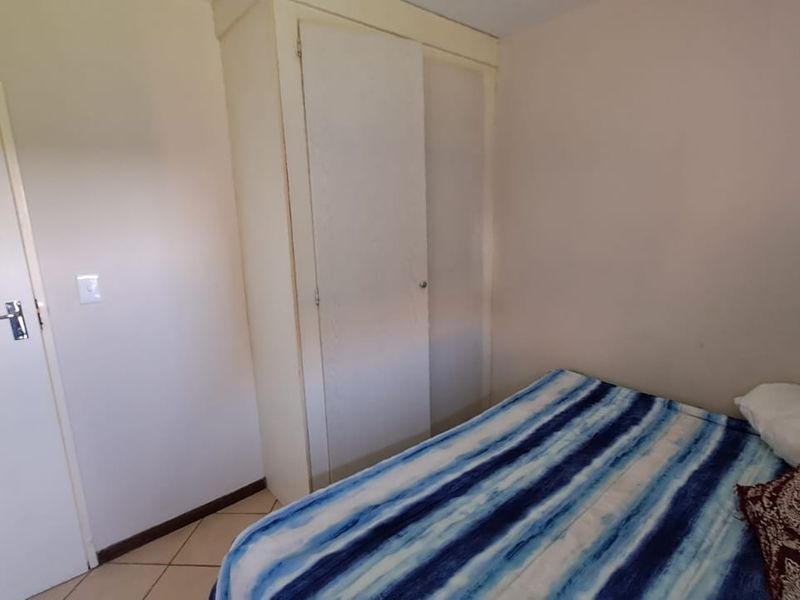 A bedroom featuring tiled flooring and a built-in wardrobe, offering a functional and neutral space.