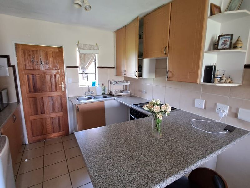 A functional kitchen featuring granite countertops, laminate cabinetry, a double basin sink, and a breakfast bar, with ceramic tile flooring throughout.