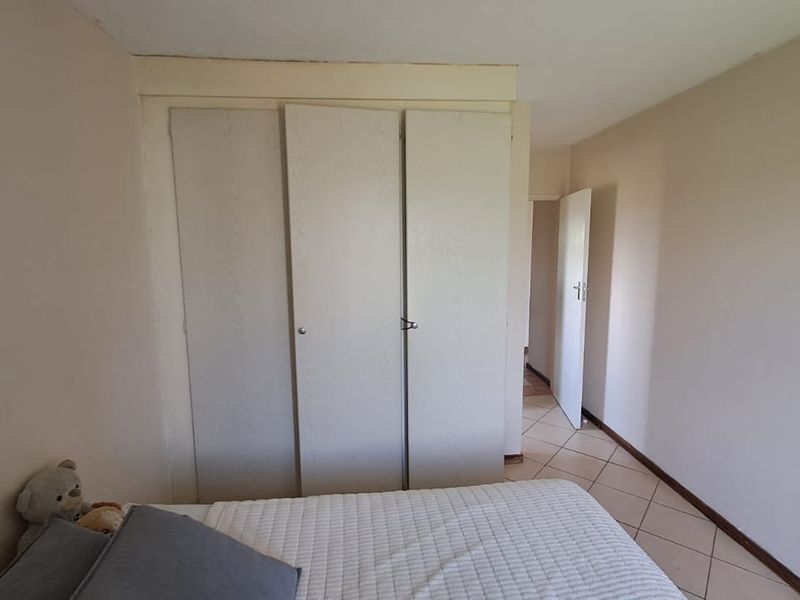 A bedroom featuring built-in cupboards and tiled flooring, requiring minor cosmetic updates to improve its overall appeal.