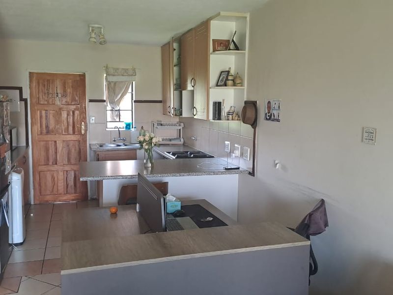 Open plan kitchen and living area featuring built-in cabinetry, laminate countertops, and tiled flooring, offering a functional layout for daily living.
