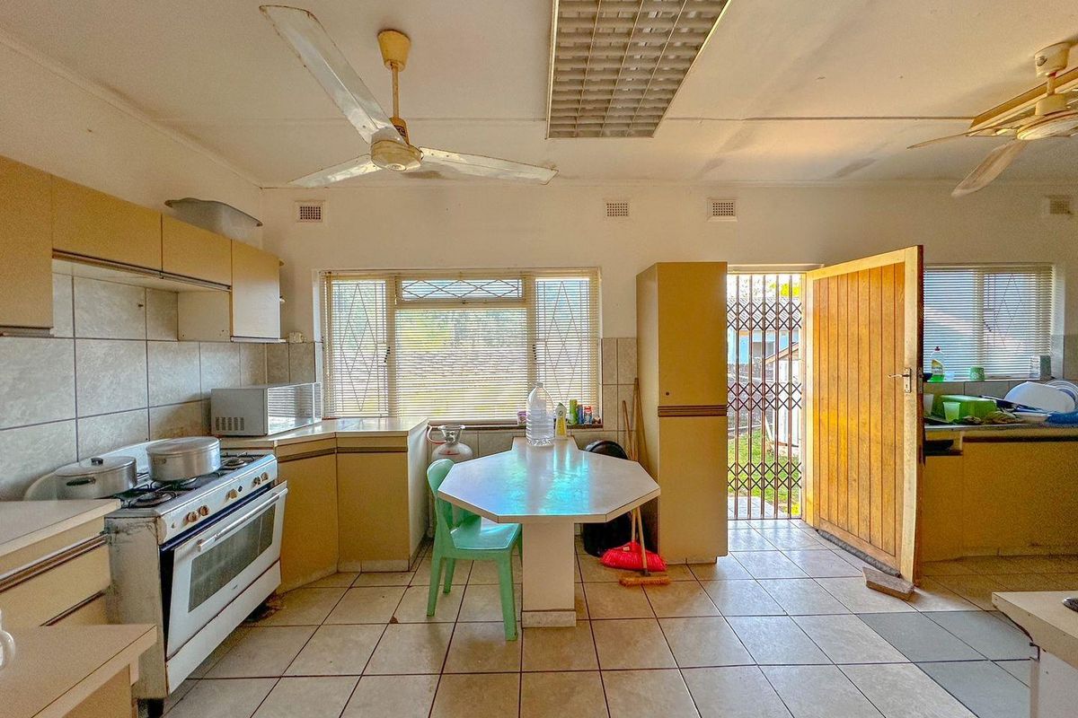 A dated kitchen featuring original cabinetry, tiled flooring, and a built-in breakfast nook, offering significant potential for a modern renovation.