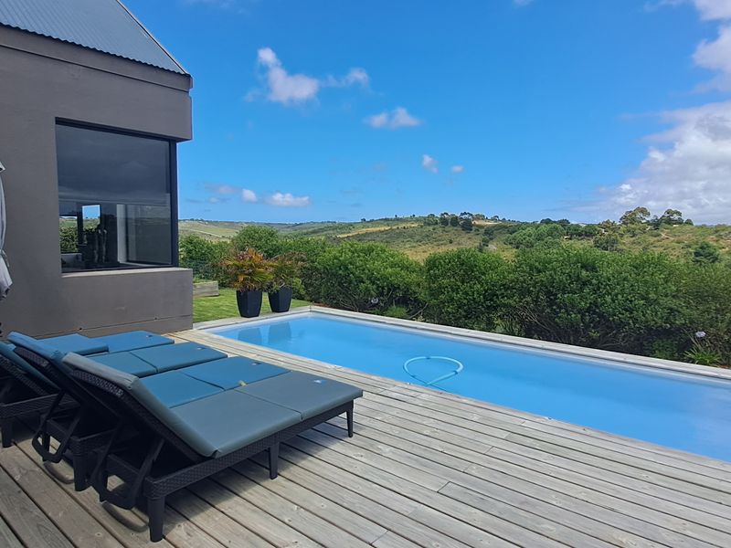A modern outdoor pool area featuring timber decking and a swimming pool, set against a scenic landscape view.